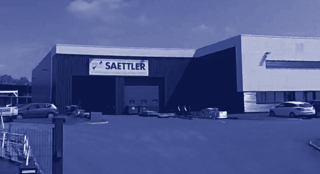 Vue de l'atelier Saettler traitée en bleu : le hall, l'enseigne et les portes de fabrication.